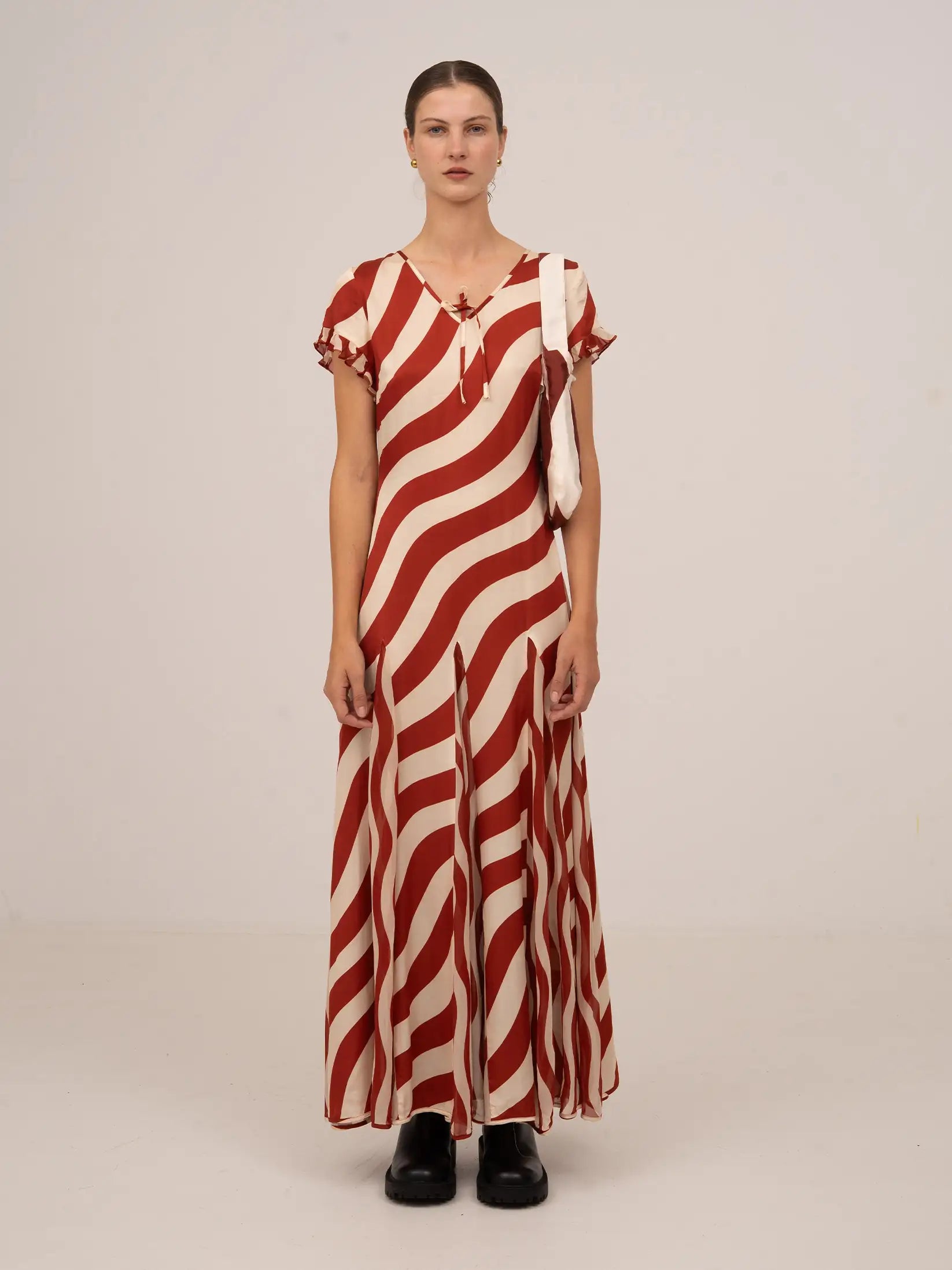 Vestido largo de manga corta con estampado de rayas onduladas en tonos rojo y blanco, escote en pico y caída fluida.