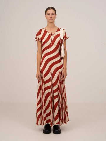 Vestido largo de manga corta con estampado de rayas onduladas en tonos rojo y blanco, escote en pico y caída fluida.