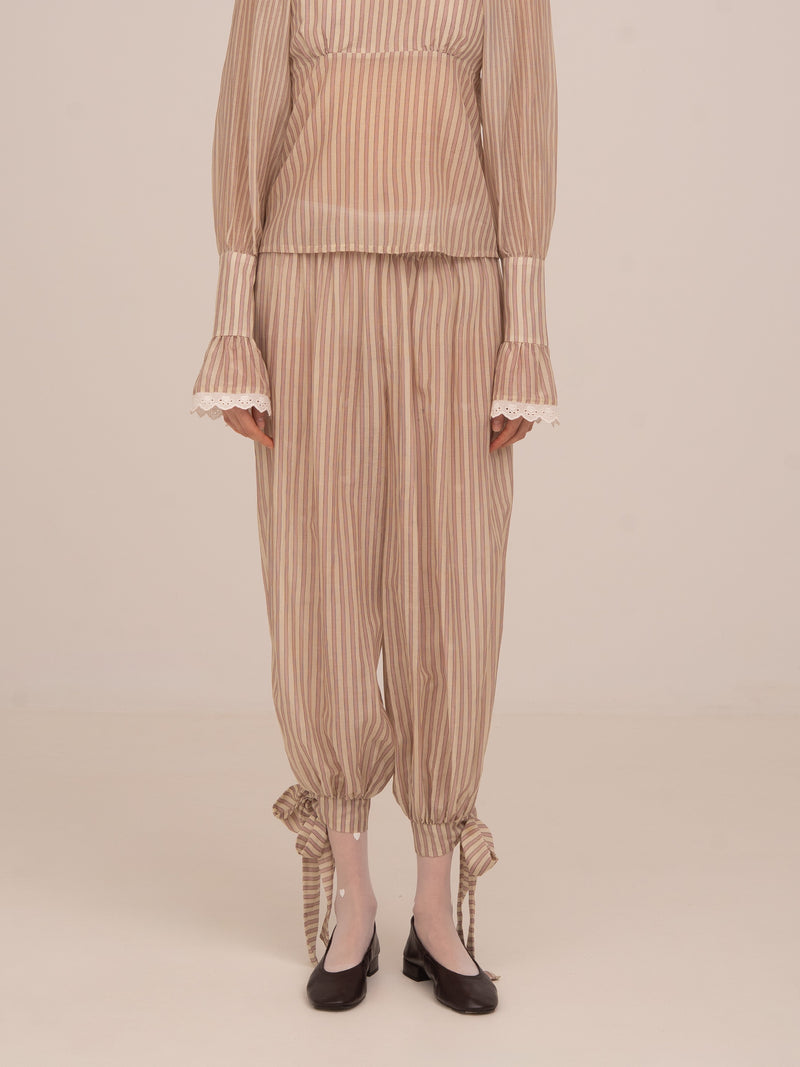 Pantalón de rayas rosa y beige de Carmen Says con bajo ajustable y lazadas en el tobillo, diseño fluido y femenino ideal para conjuntos elegantes y ocasiones especiales.