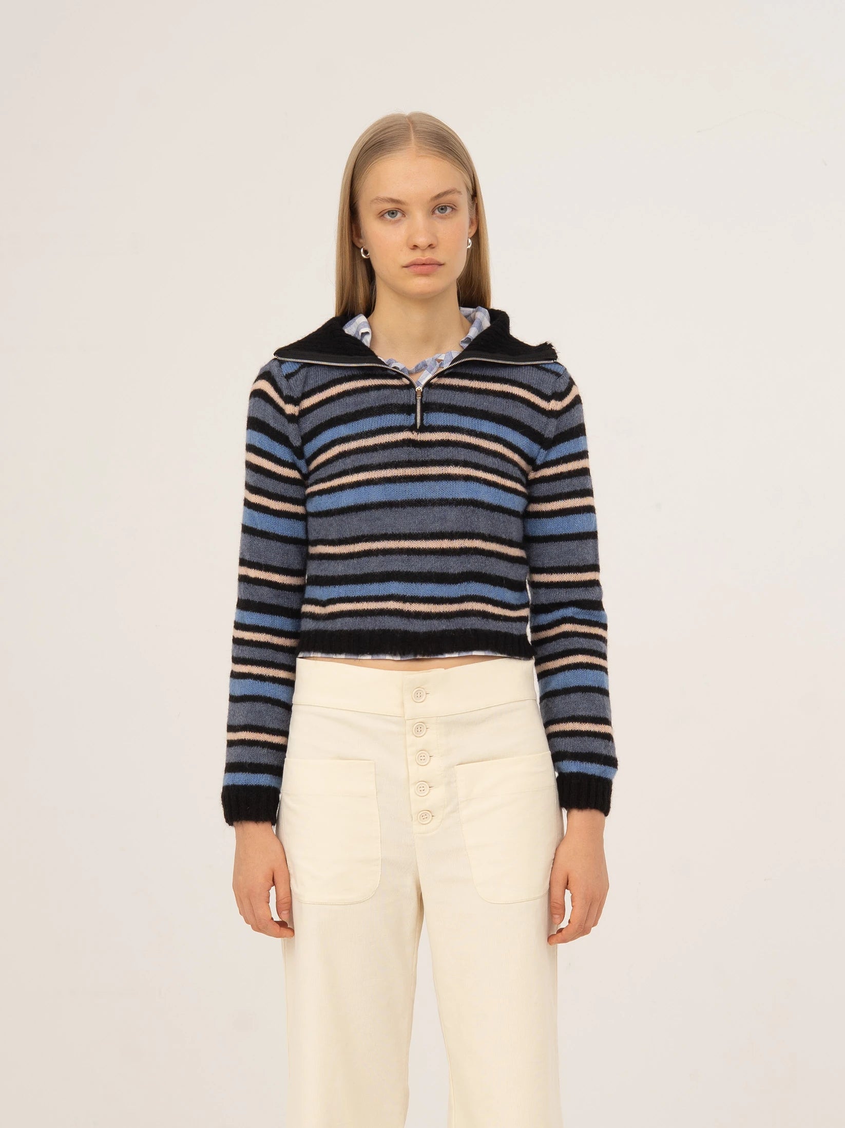 Top de punto a rayas en tonos azul y negro, con cuello tipo polo, manga larga y silueta ajustada, presentado sobre modelo en estudio con fondo neutro.