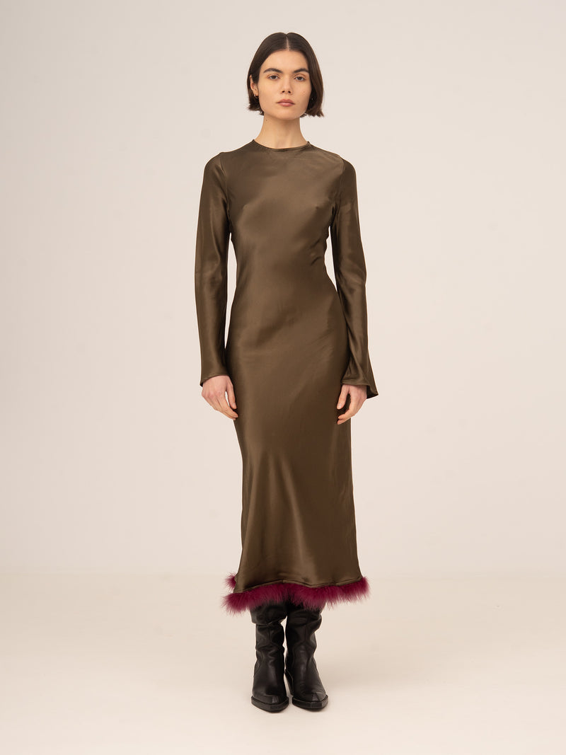 Vestido largo femenino en color marrón con acabado satinado, diseño entallado de manga larga y detalle de plumas en el bajo, elegante y sofisticado para eventos especiales, cenas de noche o looks de fiesta exclusivos.