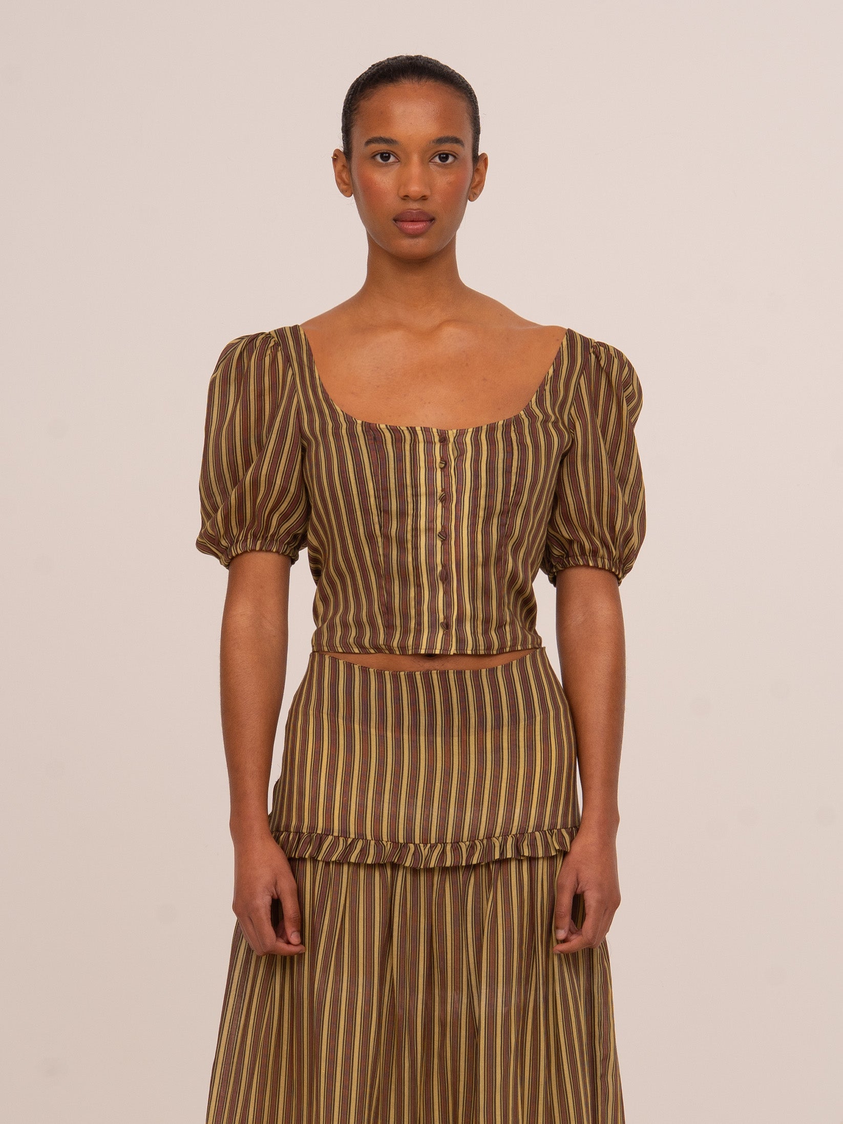 Top de mujer en tonos marrón y verde con estampado de rayas verticales, diseño de manga corta abullonada y silueta ajustada.