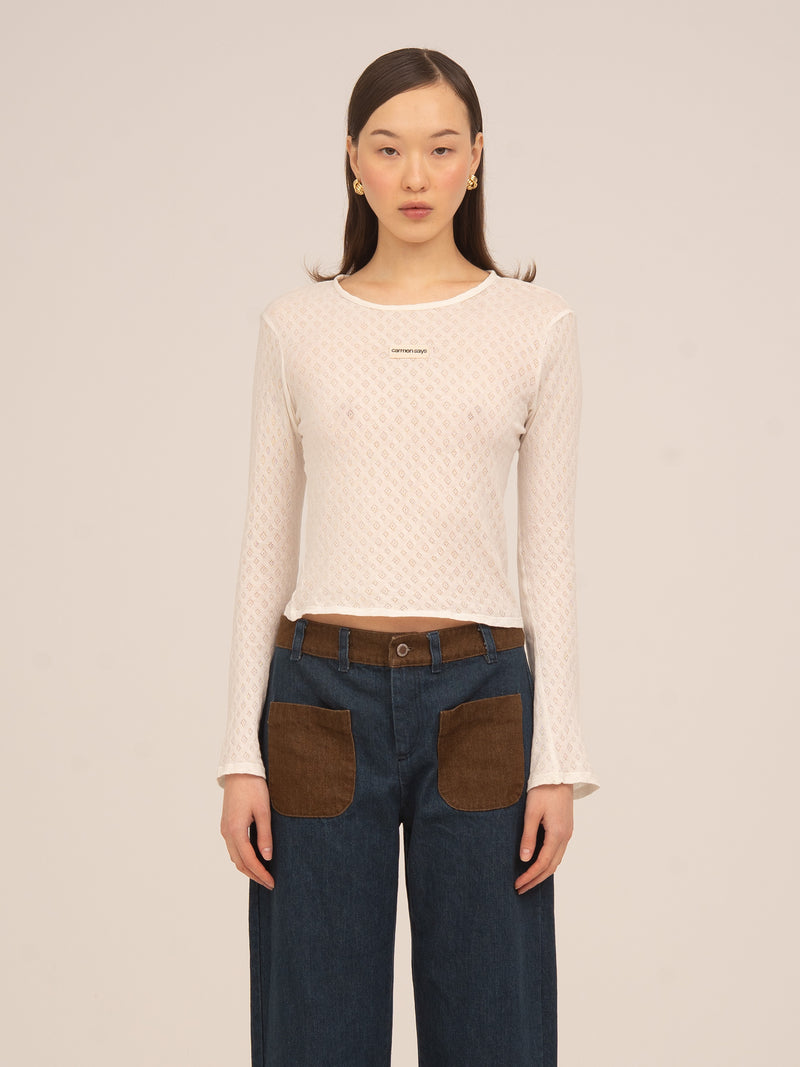 Top blanco de manga larga de Carmen Says en tejido jersey ligero con textura sutil, diseño femenino y versátil ideal para looks elegantes y conjuntos sofisticados de diario.