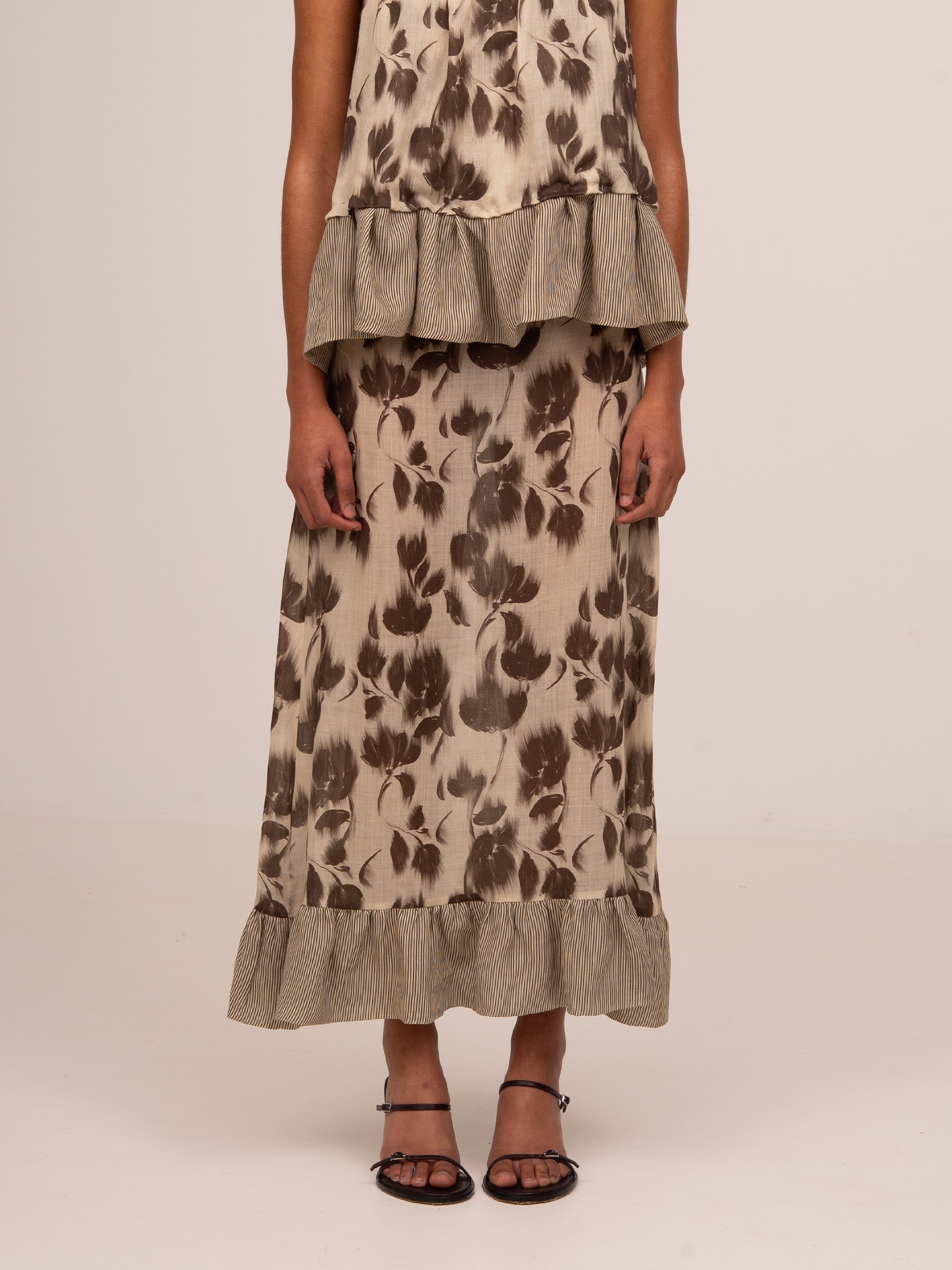 Falda midi con estampado floral marrón, silueta fluida y bajo con volante fruncido en contraste de rayas.