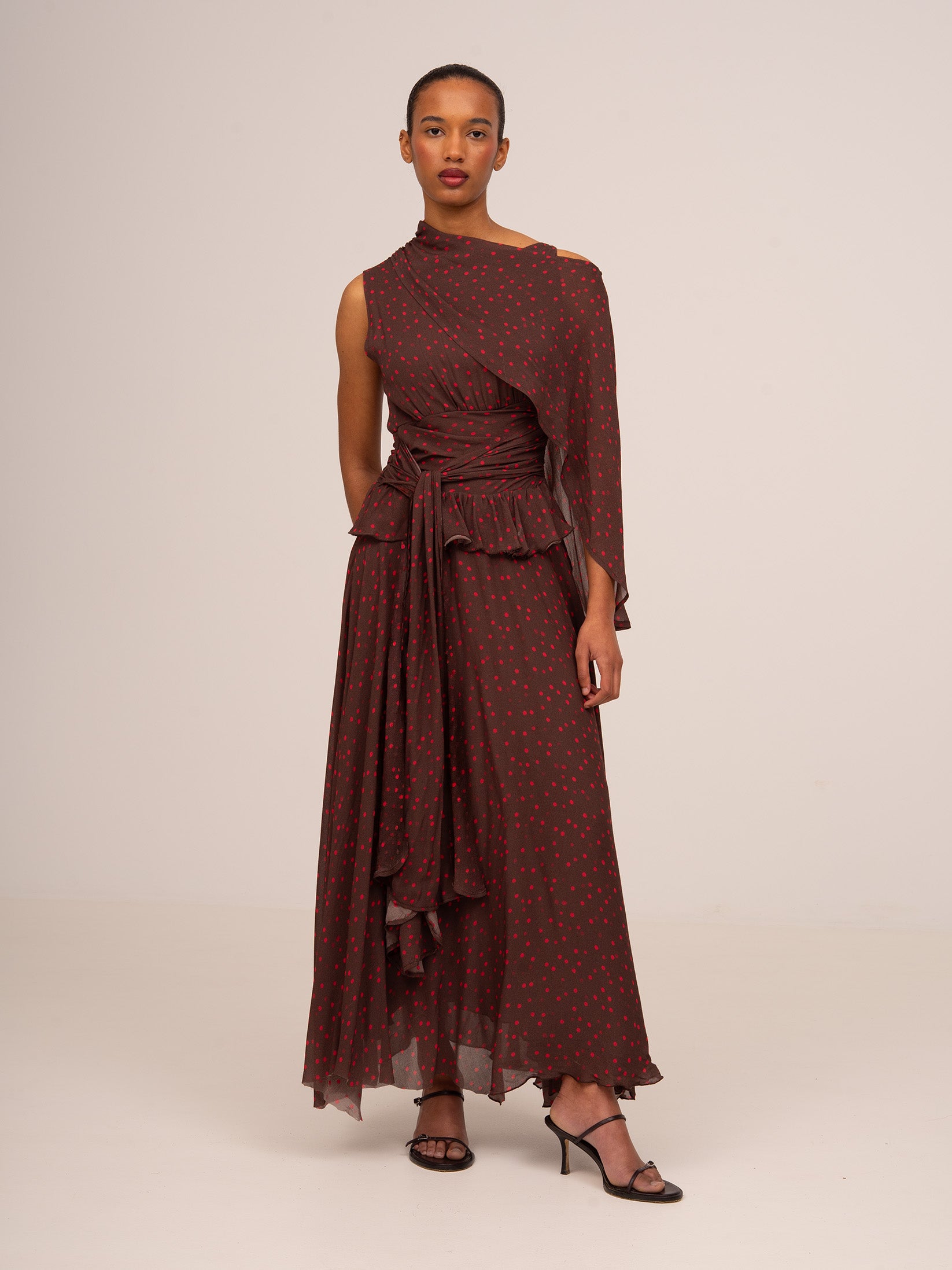 Vestido largo de mujer en color marrón con estampado de lunares rojos, diseño sin mangas y detalle drapeado en la cintura.