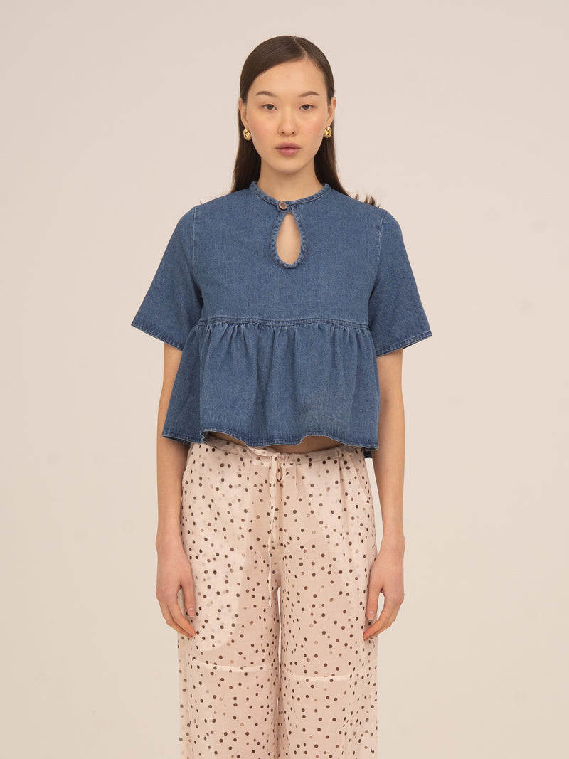 Top denim azul de Carmen Says con manga corta, corte cropped y detalle de abertura en el escote, diseño femenino y actual ideal para looks urbanos con un toque sofisticado.