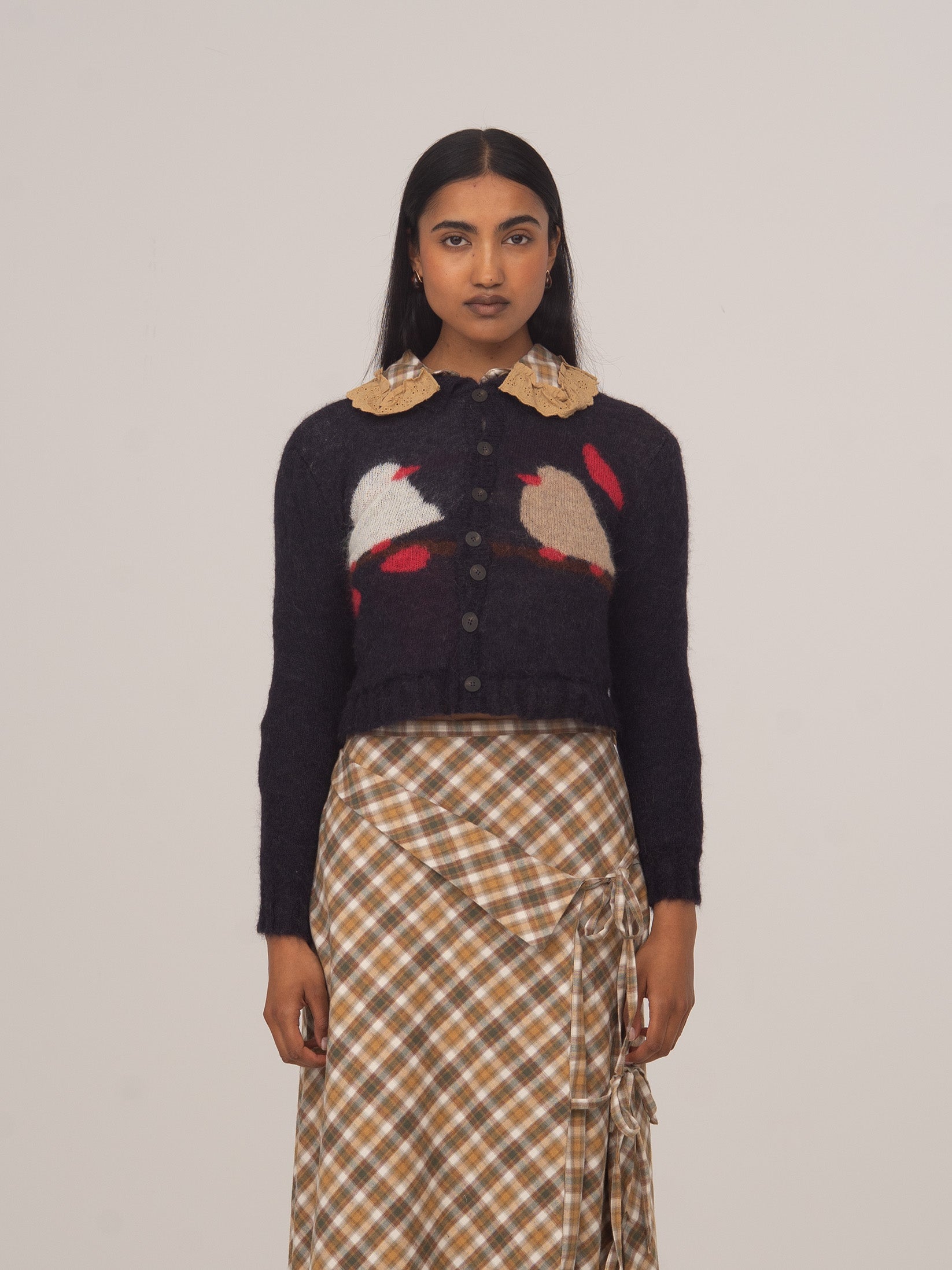 Modelo con cárdigan de punto azul Carolina de CARMEN SAYS con estampado de aves, combinado con falda de cuadros