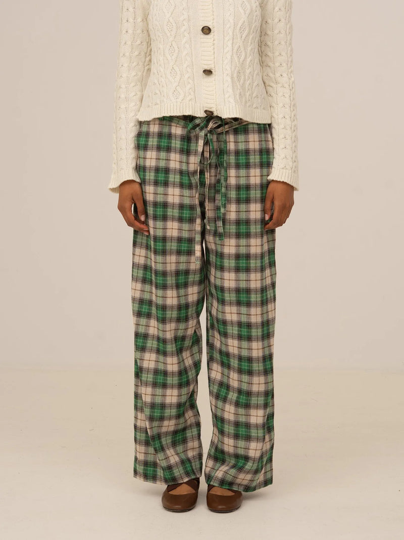 Pantalón largo de cuadros verdes tipo tartán, corte recto y cintura con cordón ajustable, presentado sobre modelo en estudio con fondo neutro.