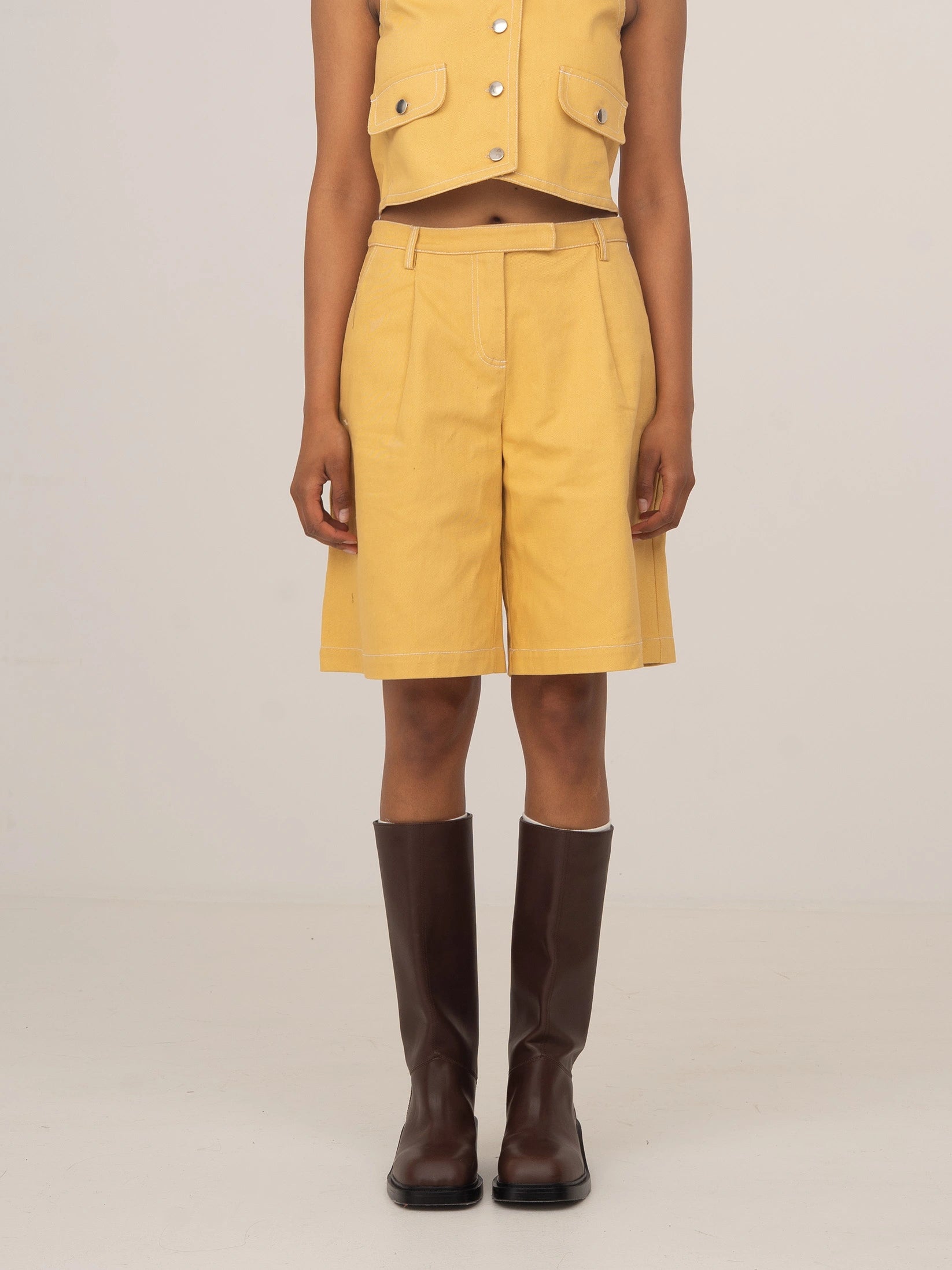Modelo con bermudas de denim amarillo pálido a juego con chaleco corto de CARMEN SAYS