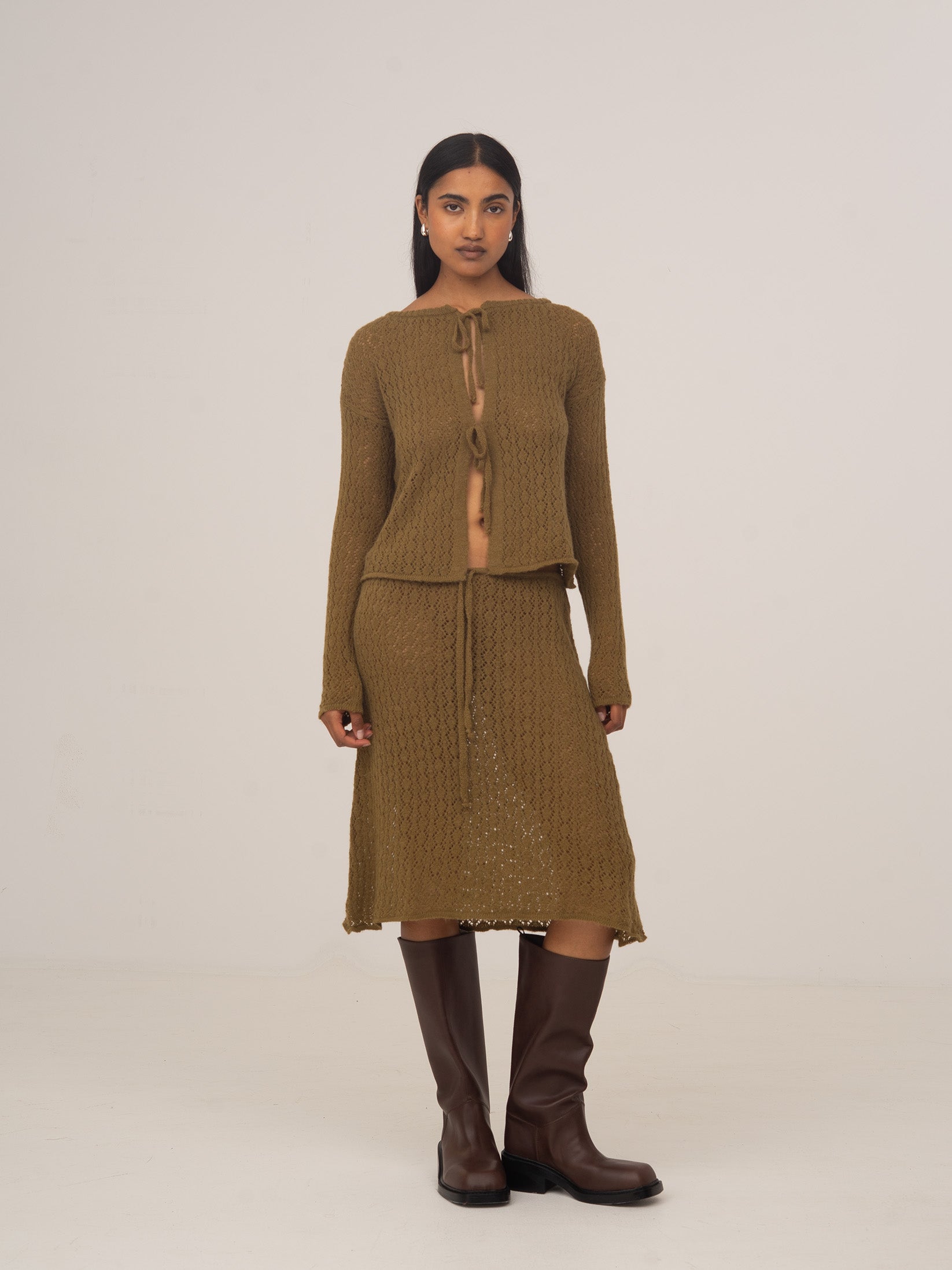 Modelo con falda midi de punto verde CARMEN SAYS, combinada con cárdigan de punto y botas marrones